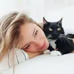 Cat cuddling owner on bed